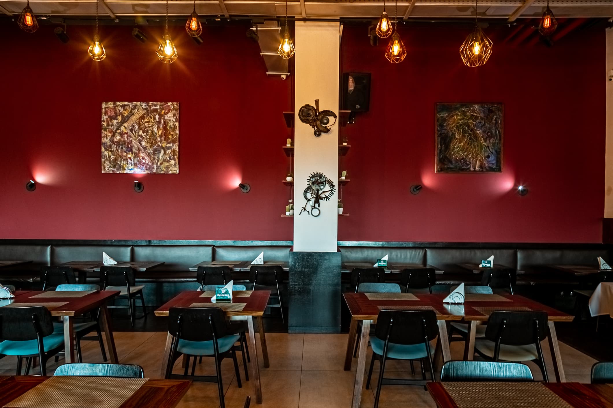 Sala interior com parede vermelha, arte e lâmpadas industriais